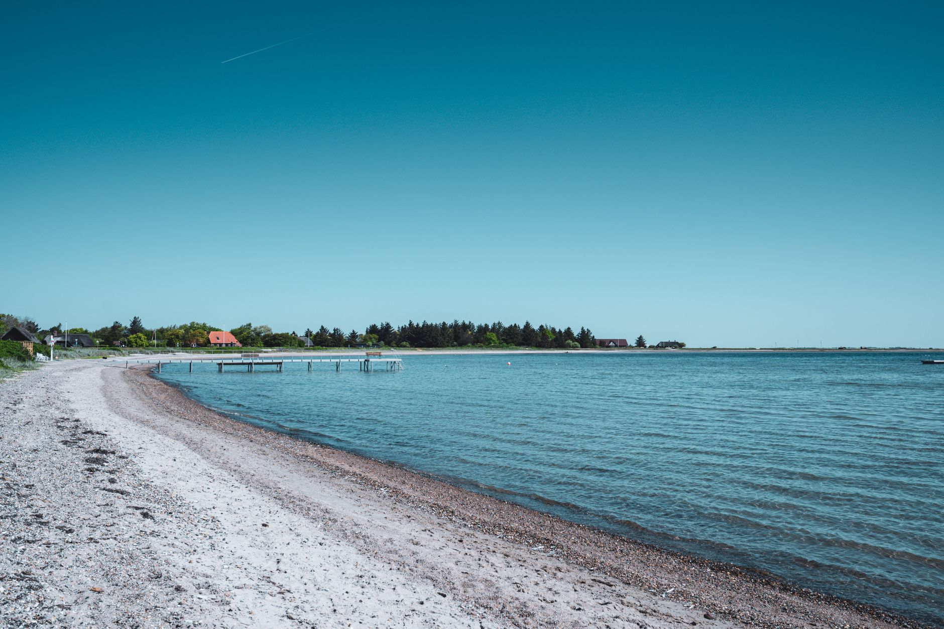 Stenet strand ved en fjord med klart blåt vand